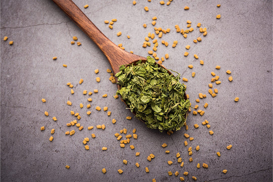 A spoonful of dried fenugreek leaves and seeds scattered around | fenugreek benefits for hair