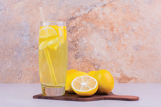 A glass of lemon juice and lemons | Is lemon juice good for your hair